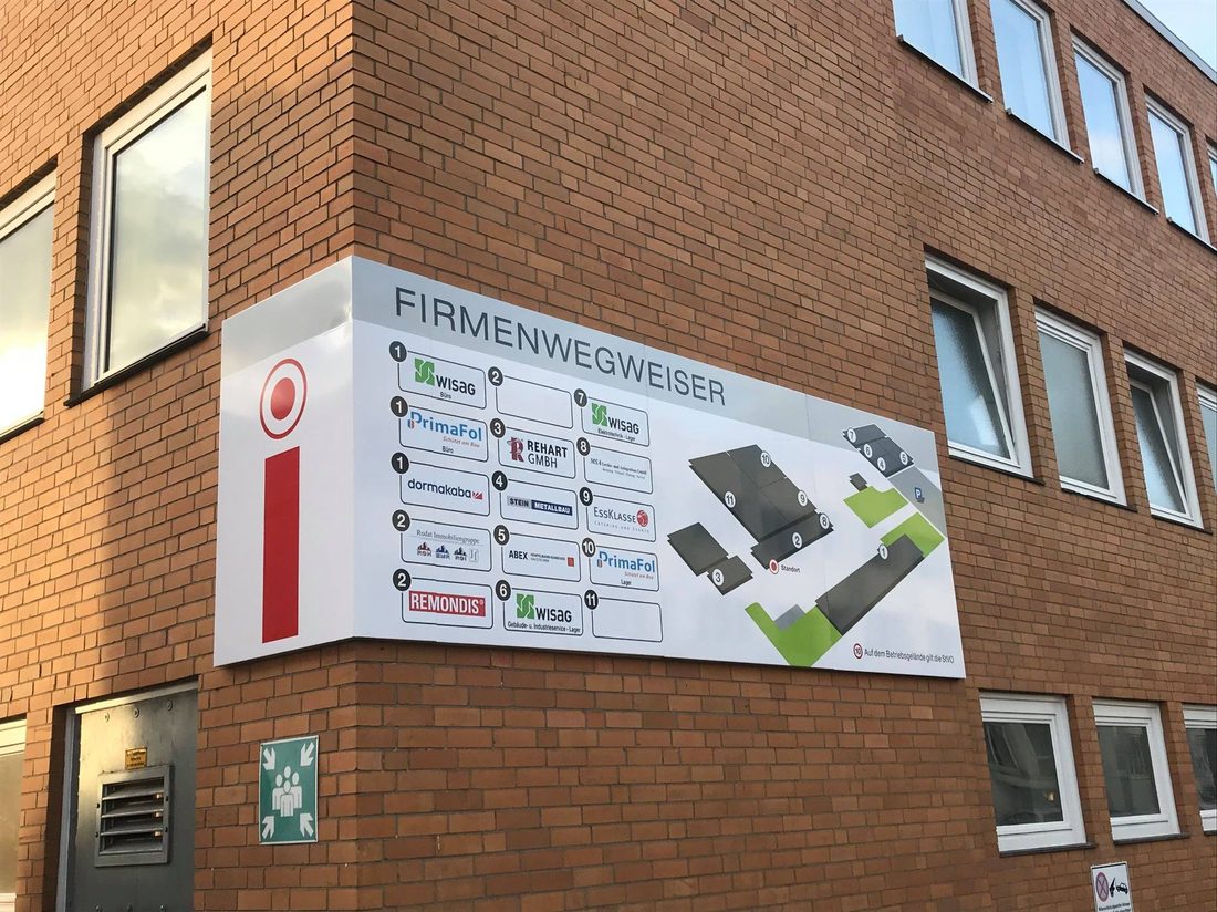 Firmenwegweiser an einer Gebäudefassade mit mehreren Firmenlogos